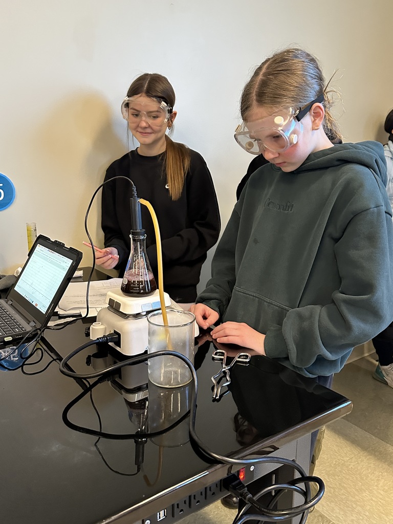 two female students at a lab station watching a distillation experiment