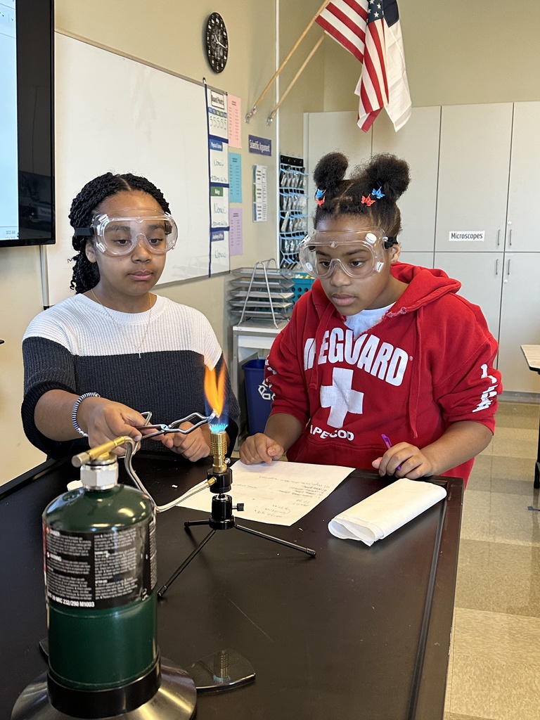 two female students performing flame tests in science class