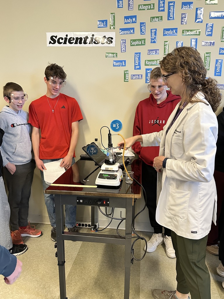 science students and their table at a lab station looking at a beaker on a burner