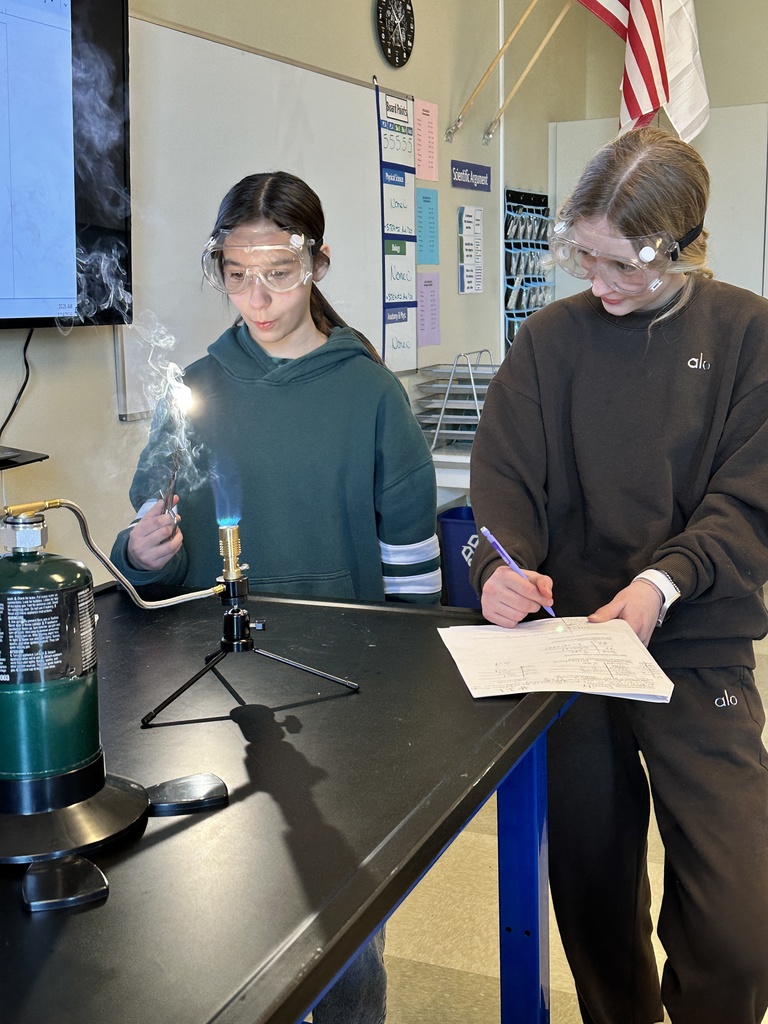 two female students performing flame tests in science class
