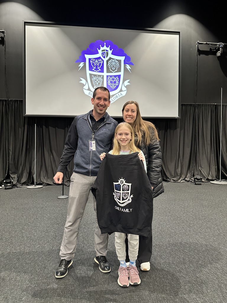 student holding her awarded sweatshirt standing with her parents