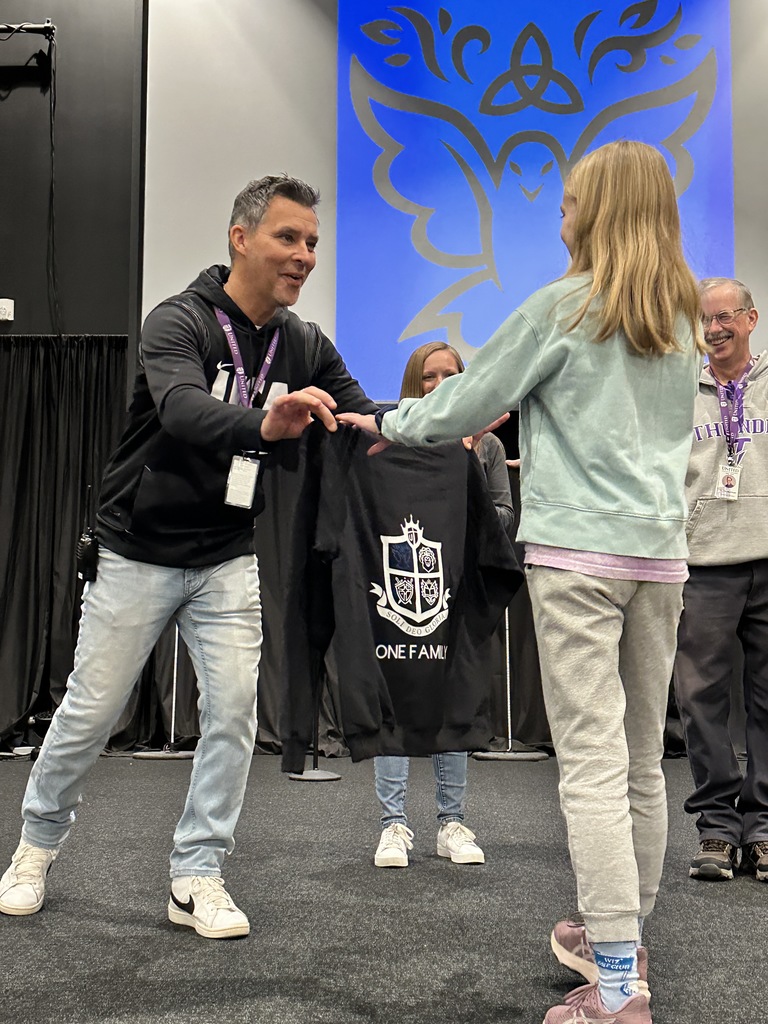 Head of School presenting a fifth grade student with a sweatshirt that she was awarded for being chosen as student of the quarter