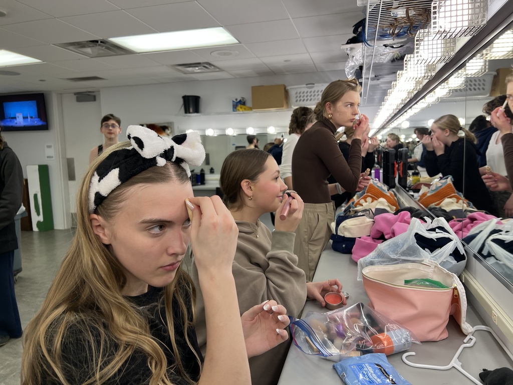 actors putting on make-up before a performance in the green room