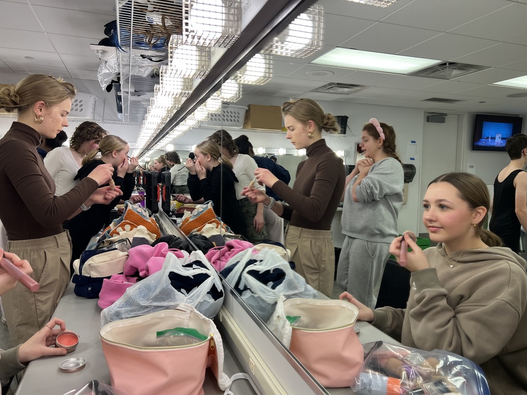 actors putting on make-up before a performance in the green room