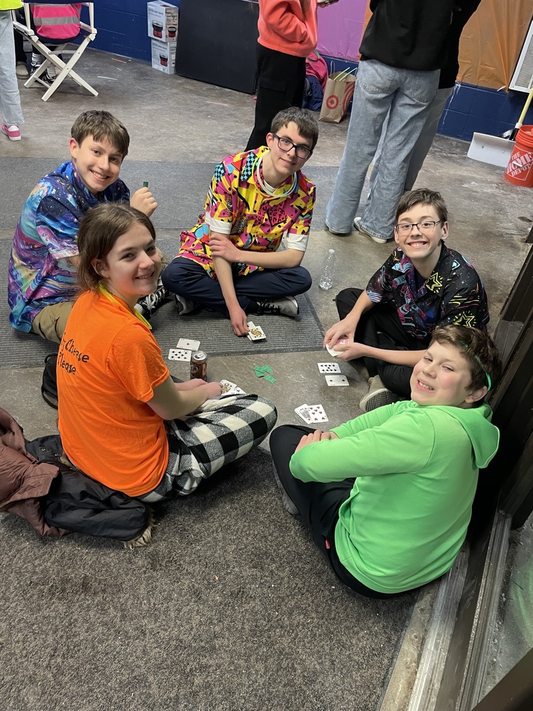 group of high school students sitting on the floor playing cards