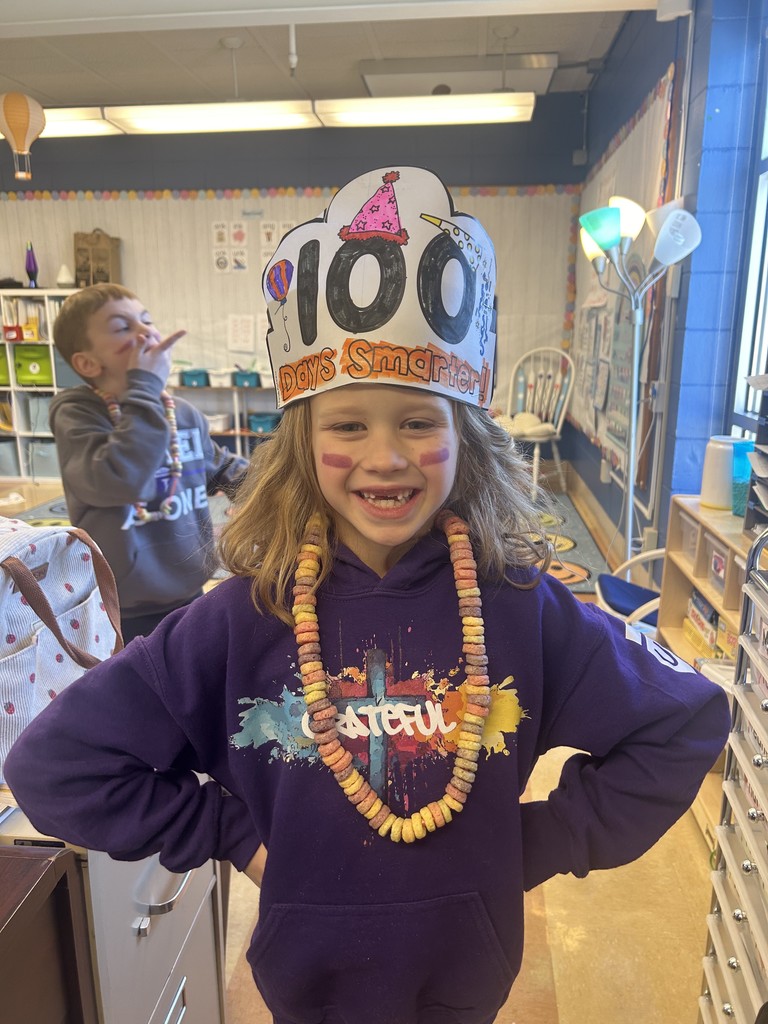 1st grade student with a hat that says "100 days smarter"