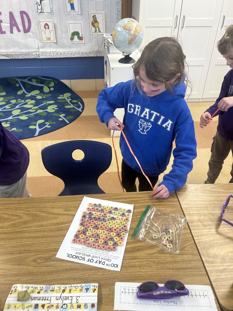 student making a necklace out of 100 fruit loops