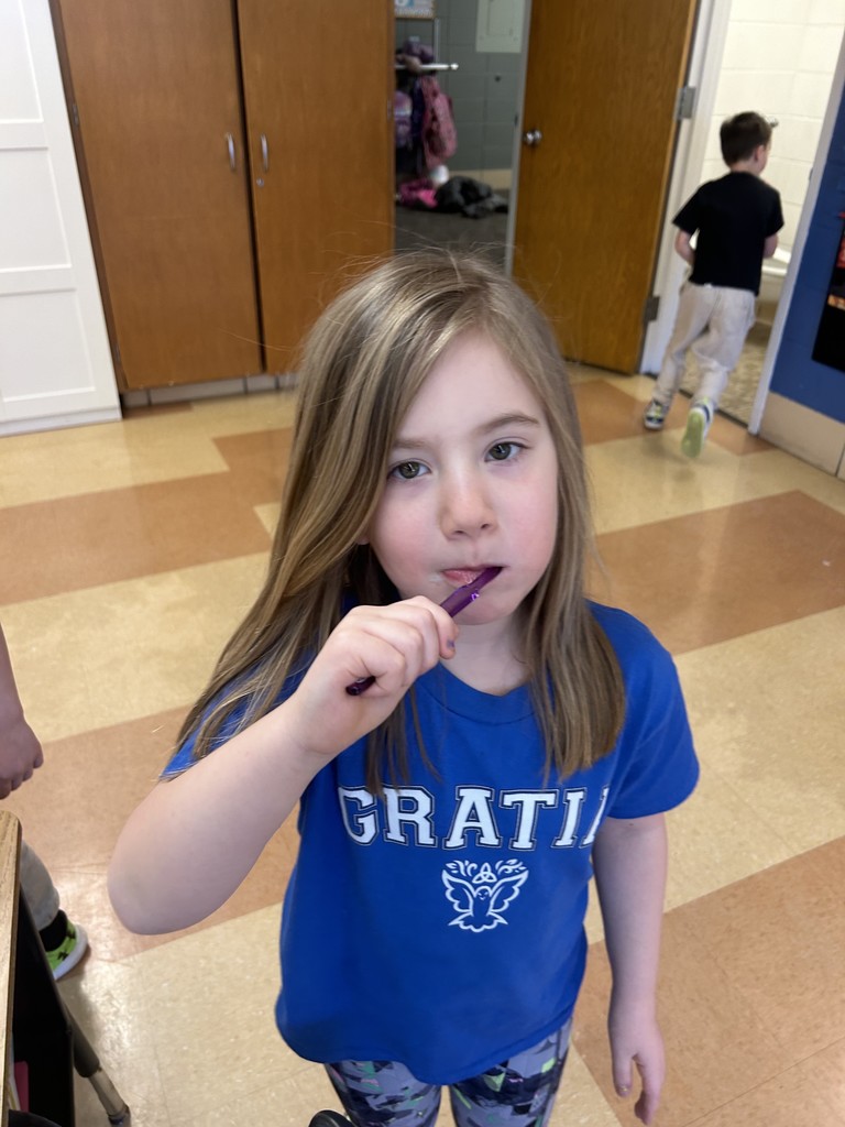 first grade student brushing her teeth