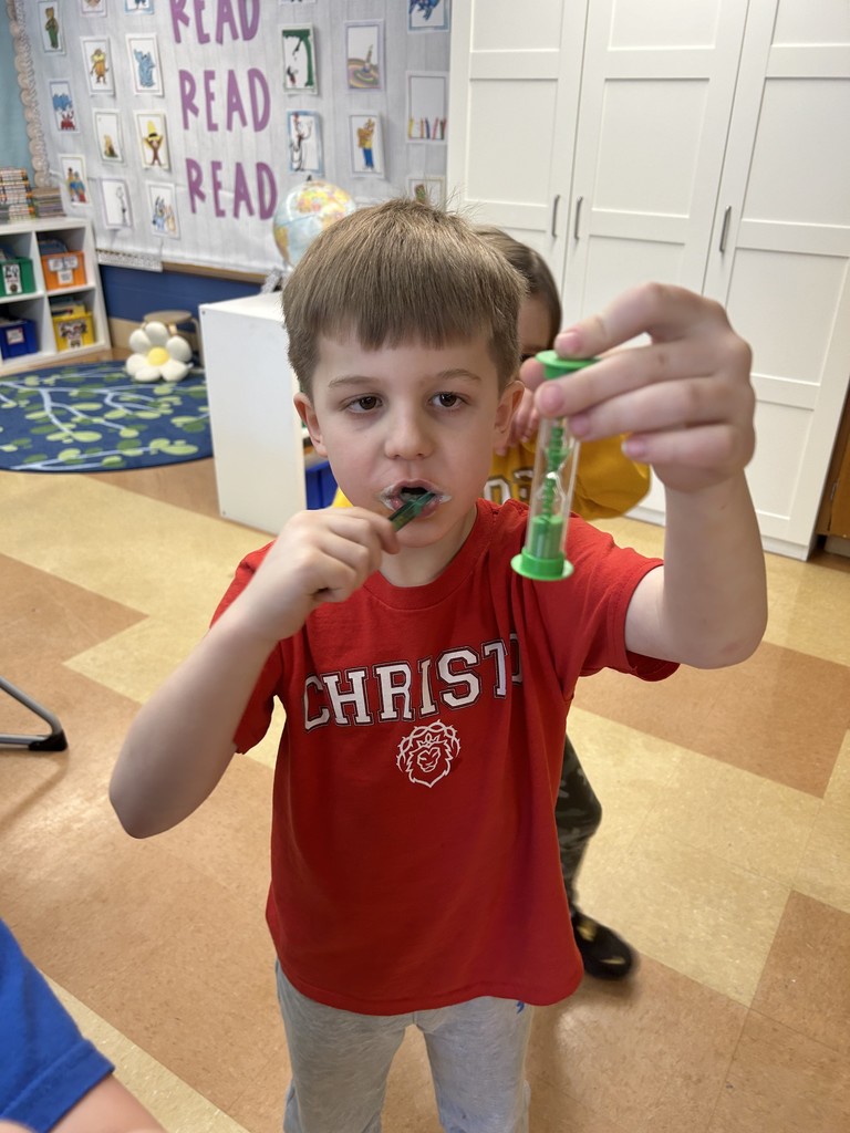 first grade student brushing his teeth while looking at a timer