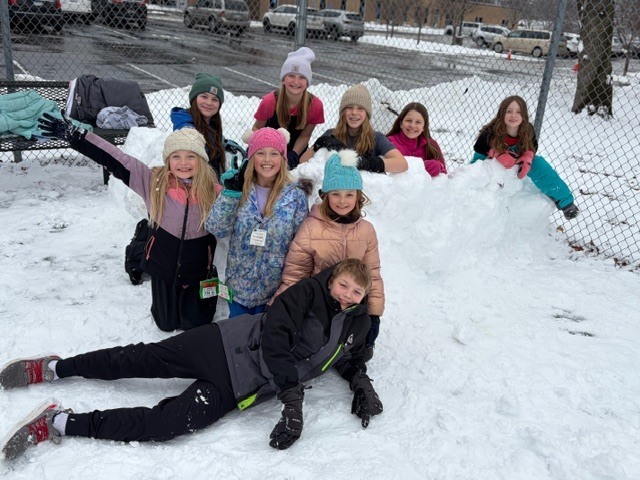 group of elementary students standing by a huge snowball