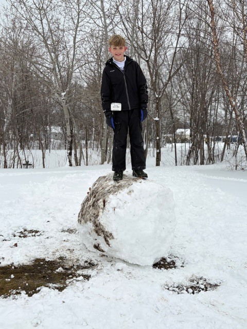 student standing on top of a large snowball