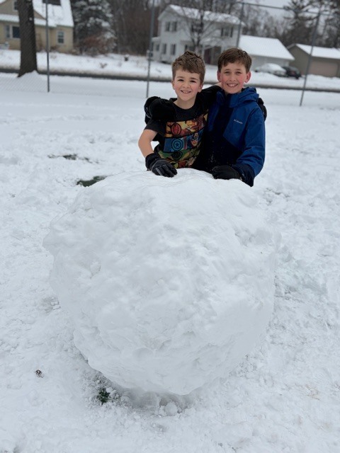 group of elementary students standing by a huge snowball