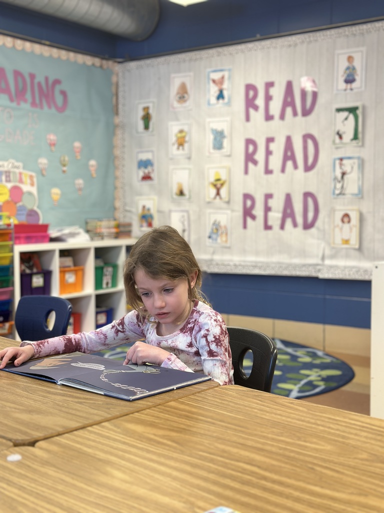 first grade student reading to herself at her desk