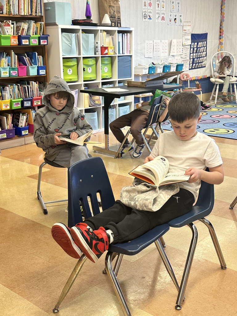 first grade students sitting in various spaces across the classroom reading to themselves