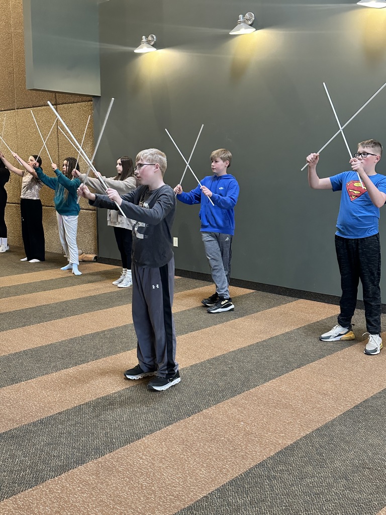 sixth grade students holding white rods which they use in a choreographed song