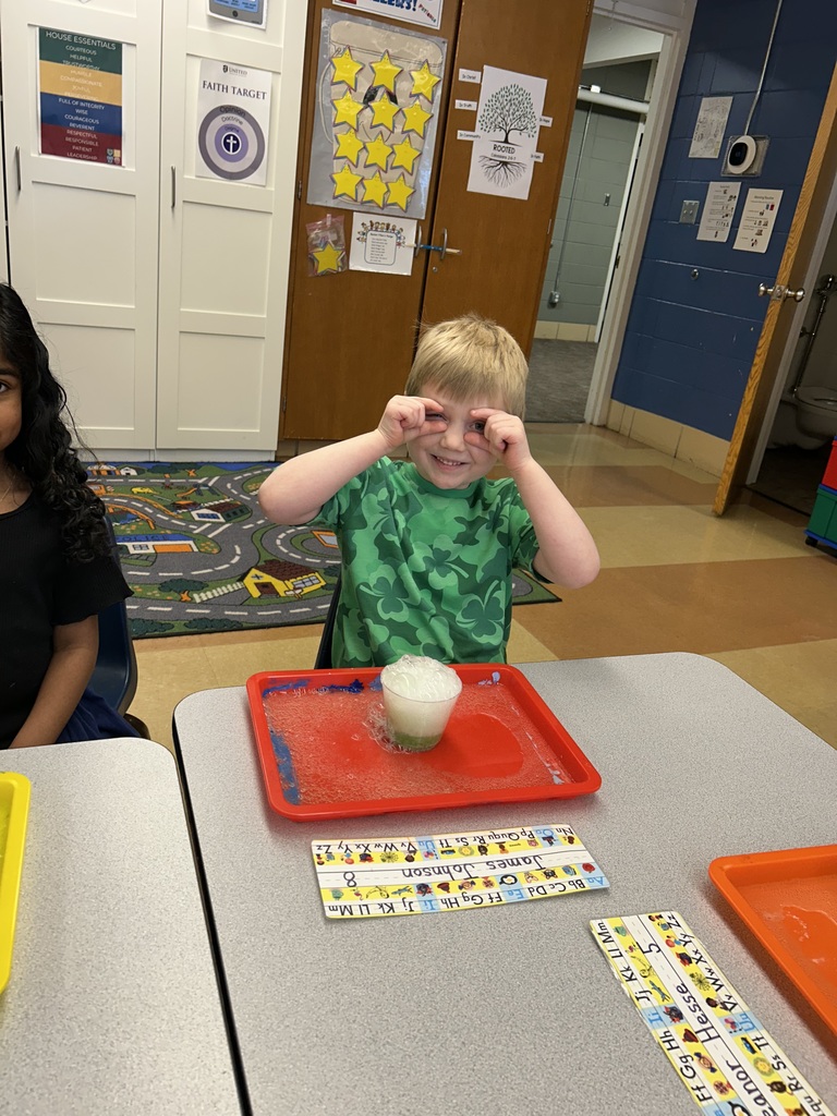a student watching a science experiment with a cup of bubbling solution sitting on his desk