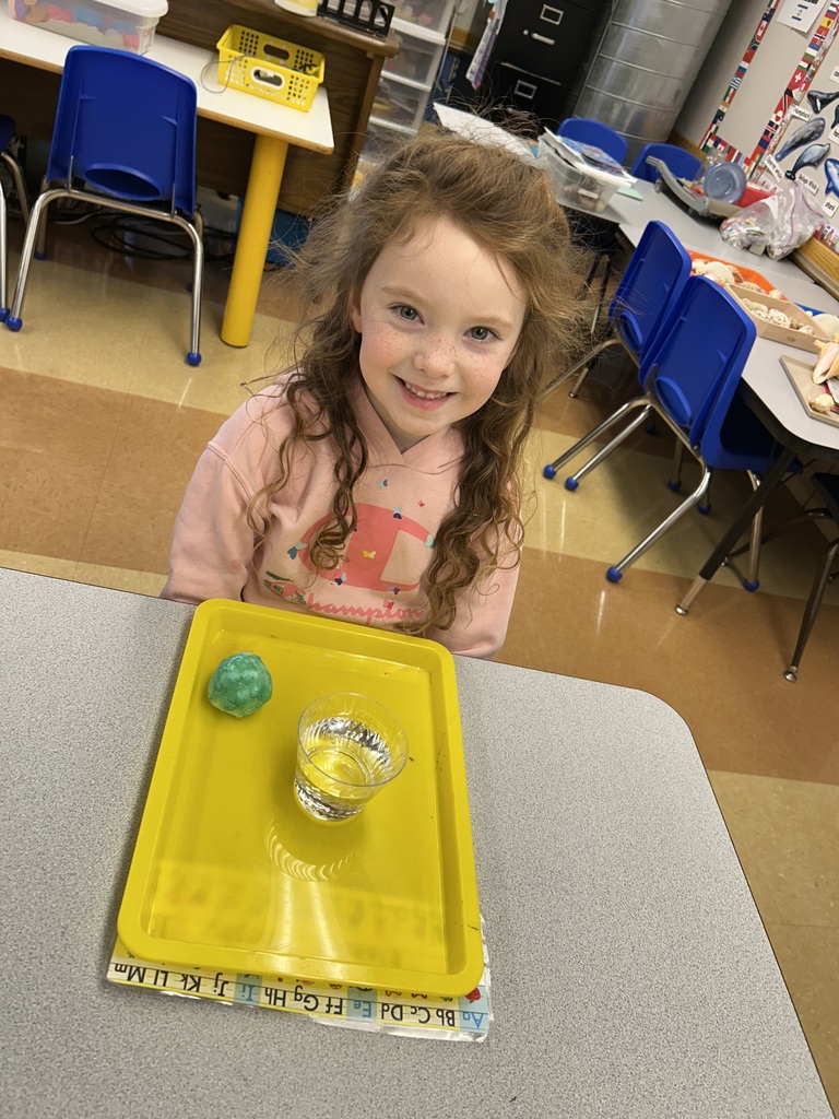 a student watching a science experiment with a cup of bubbling solution sitting on her desk