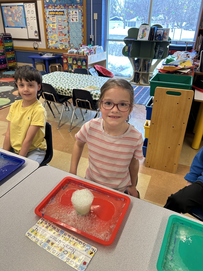 a student watching a science experiment with a cup of bubbling solution sitting on her desk
