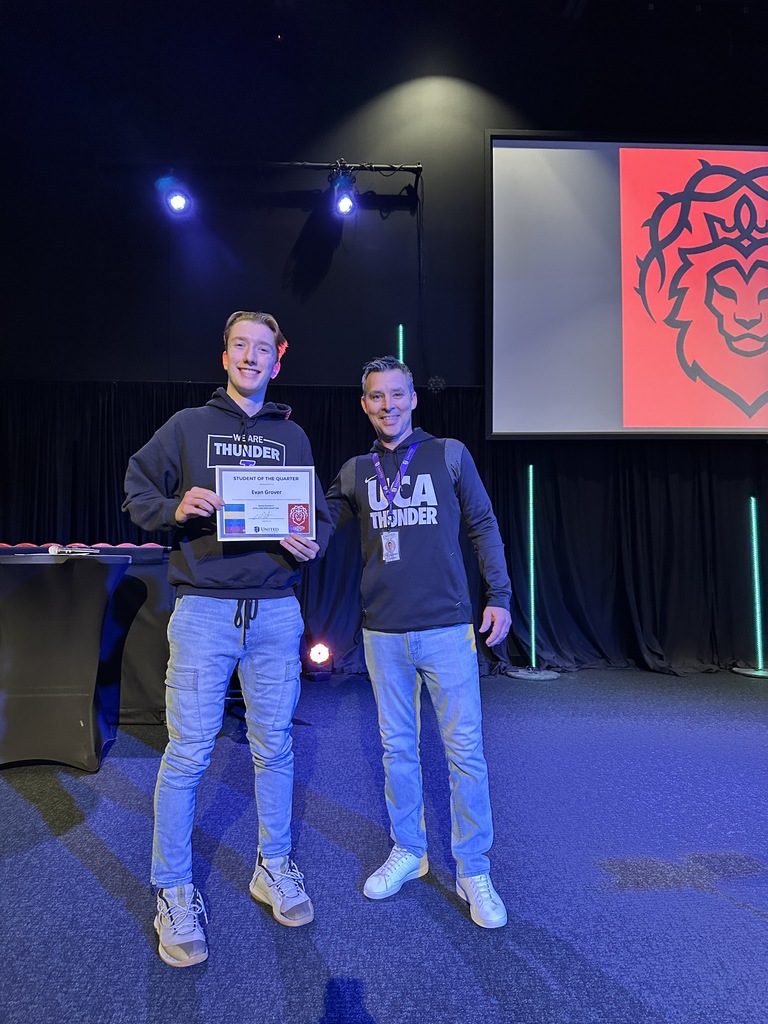 high school student holding a certificate and standing next to a teacher
