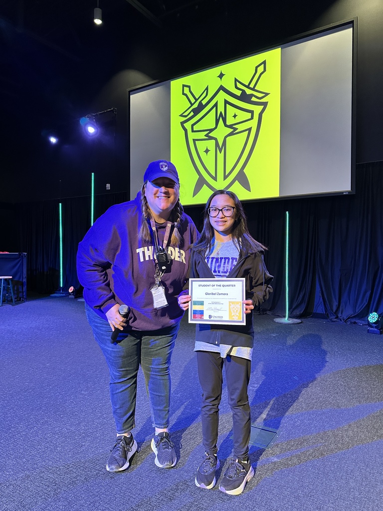 middle school student holding a certificate and standing next to a teacher