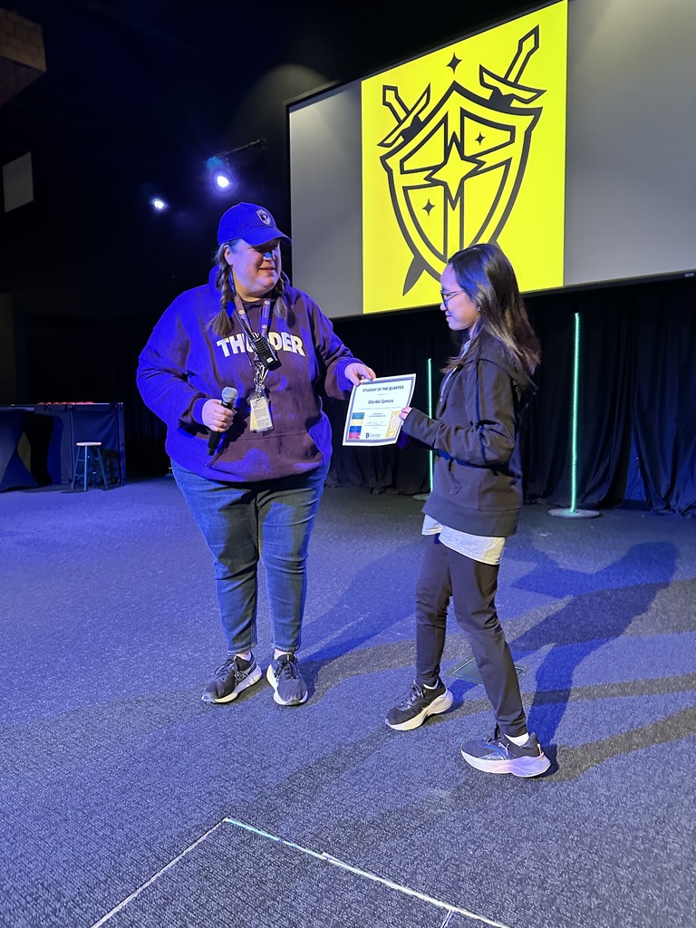 middle school teacher handing a certificate to a student