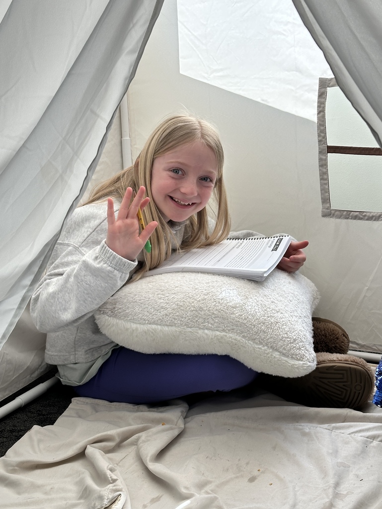 student sitting in a reading tent working on school work