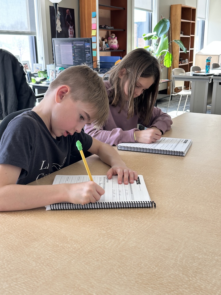 two students writing in their workbooks