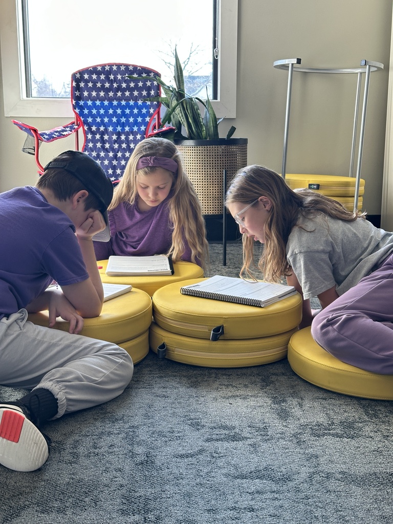 three students sitting on the floor working on a project together