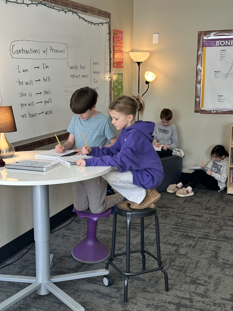 two students sitting at a table and two other students working on the floor