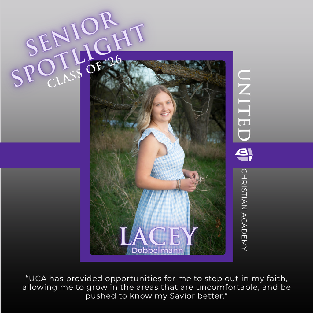 senior girl standing by a tree in a field of grass