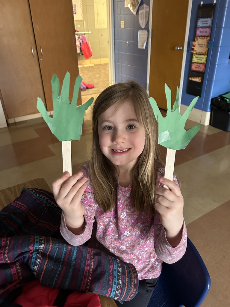 1st grade student holding up palm branches that she made