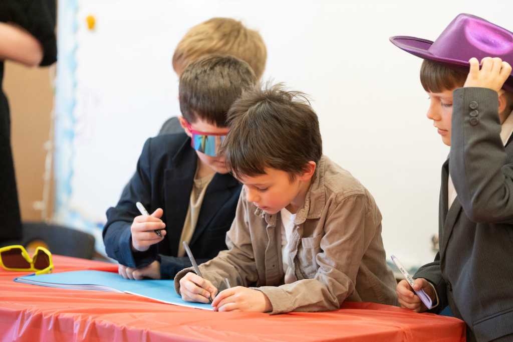 three students signing the book that they published