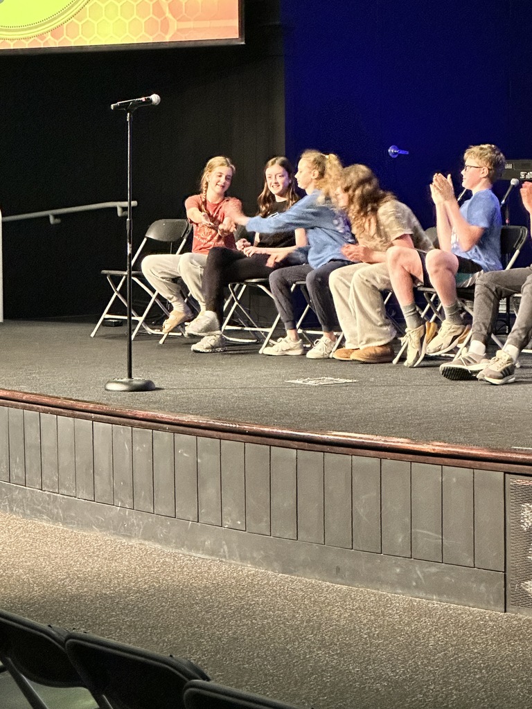 students giving each other high fives on stage during a spelling bee