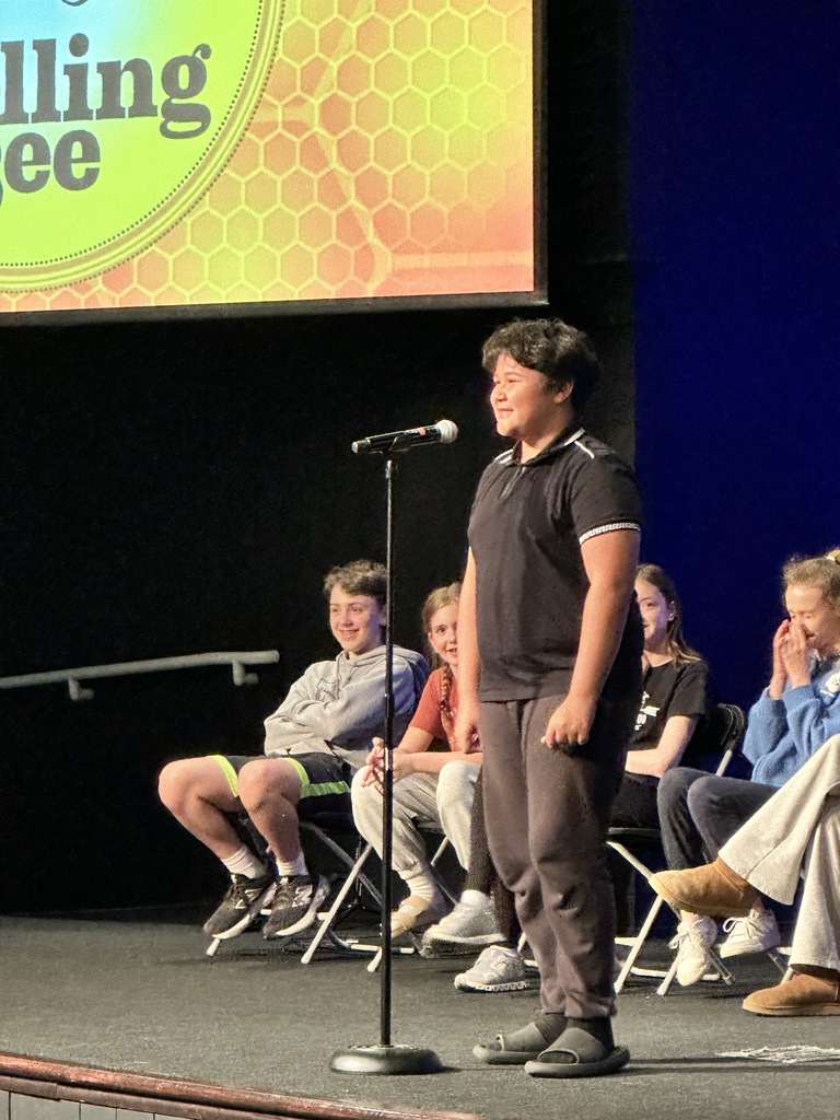middle school student standing at a microphone during a spelling bee