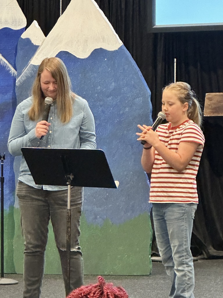 student and pastor praying on stage