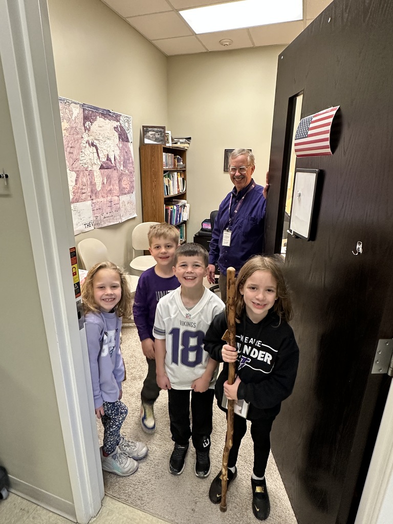 students and principal standing in the doorway of an office