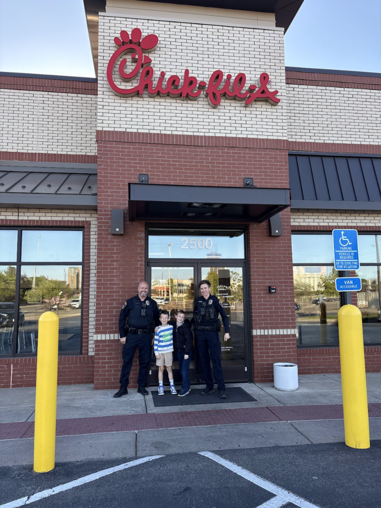 two students and two officers standing outside Chick-Fil-A