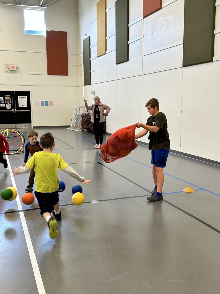 5th grade student helping younger students in gym class