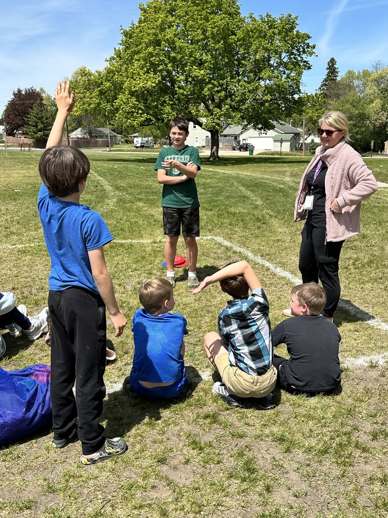 6th grade student and PE teacher standing outside with 3rd grade students