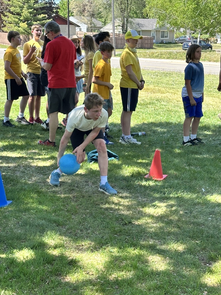 student rolling a ball in the grass