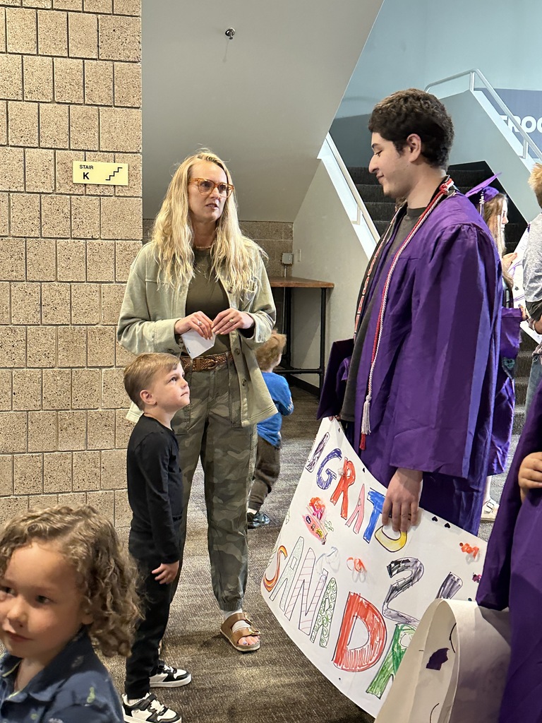 senior in cap and gown with a pre-k student