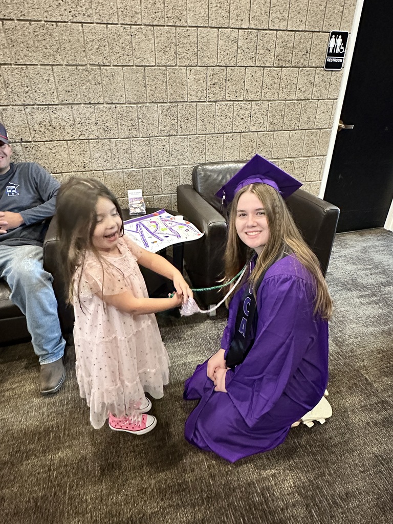 senior in cap and gown with a pre-k student
