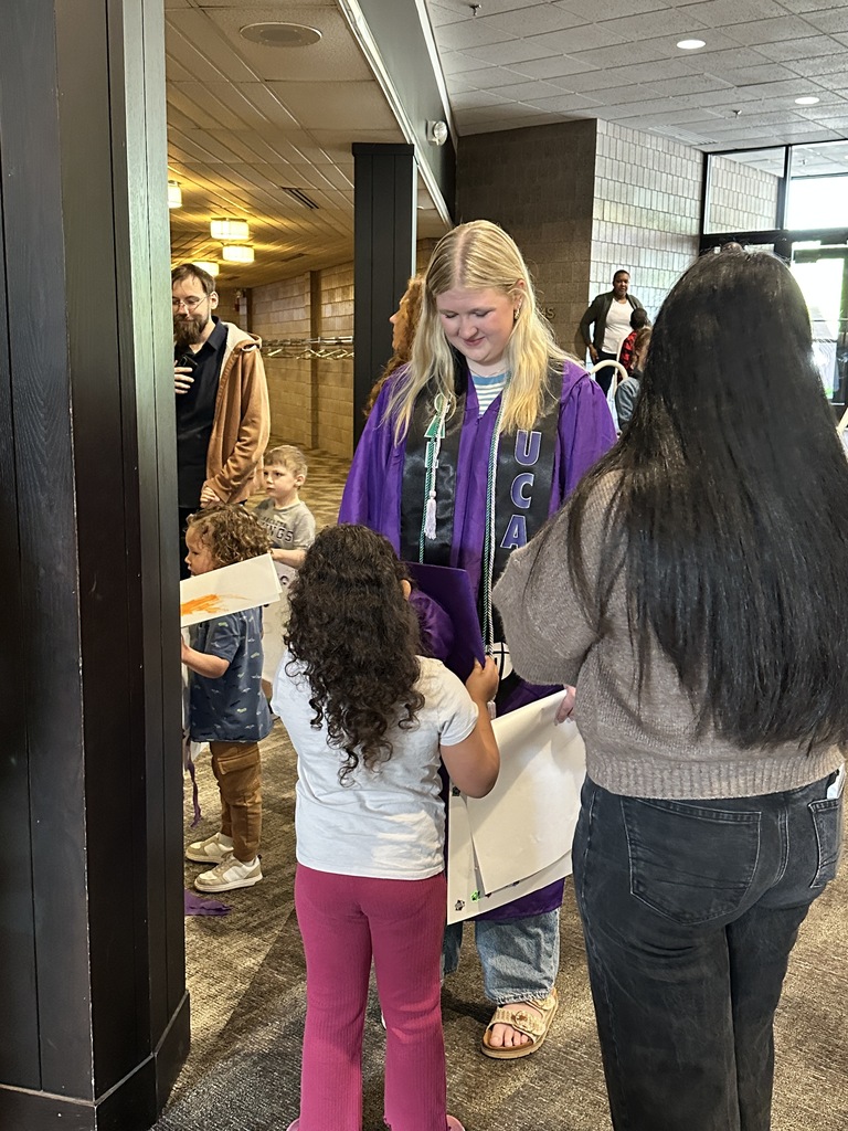 senior in cap and gown with a pre-k student