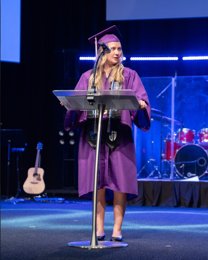 student speaking on stage at graduation