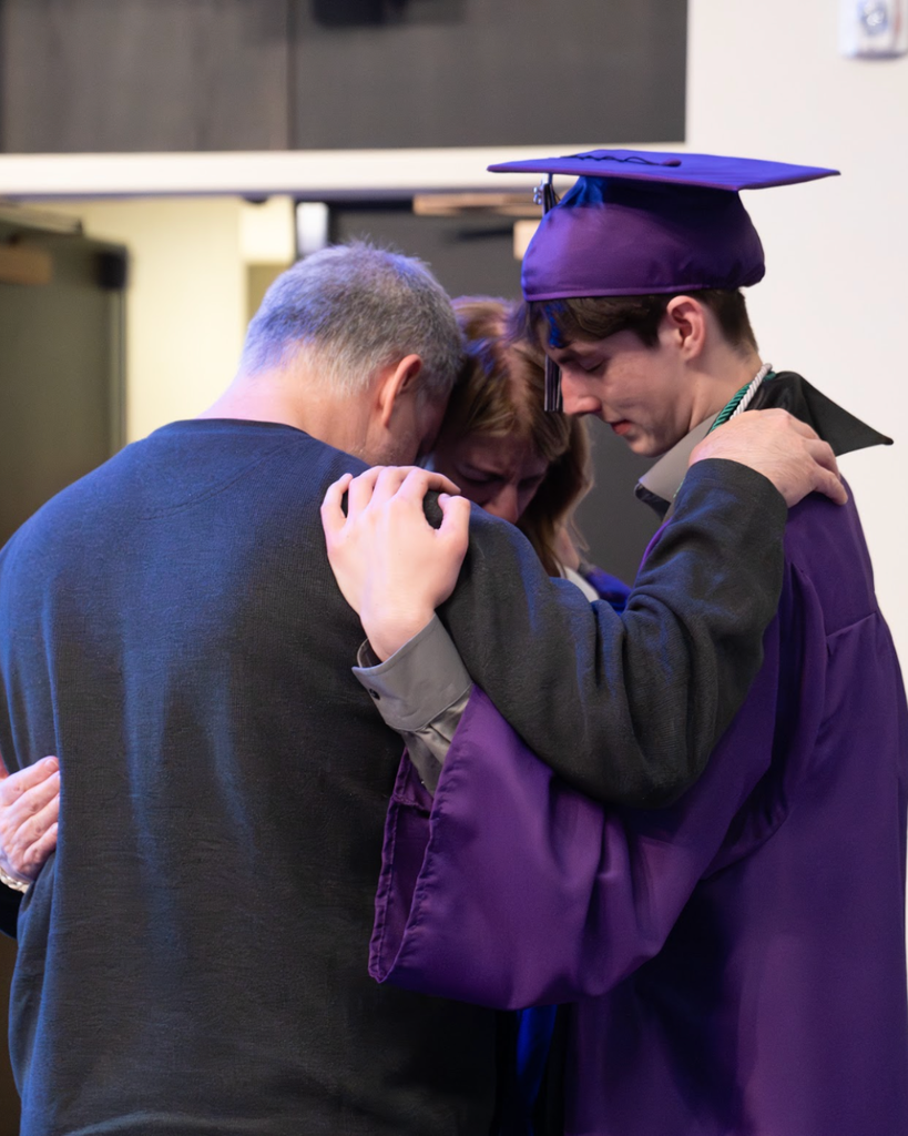 parents praying with their graduating son