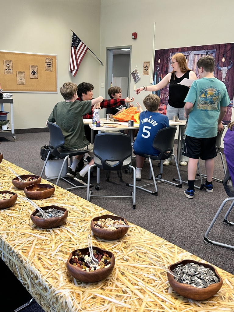 table of snacks in a classroom with teacher and students working at desks