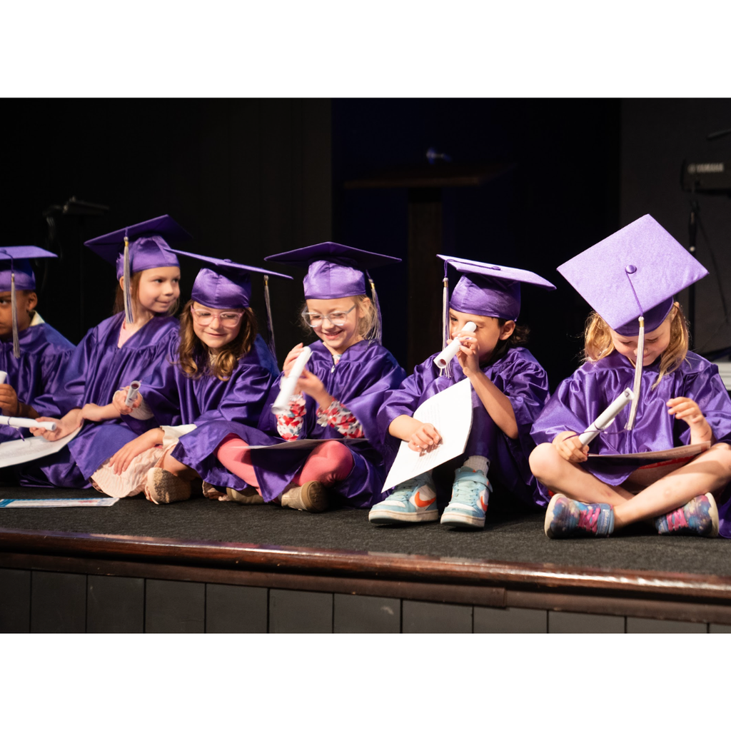 kindergarten students in caps and gowns on stage during their graduation ceremony