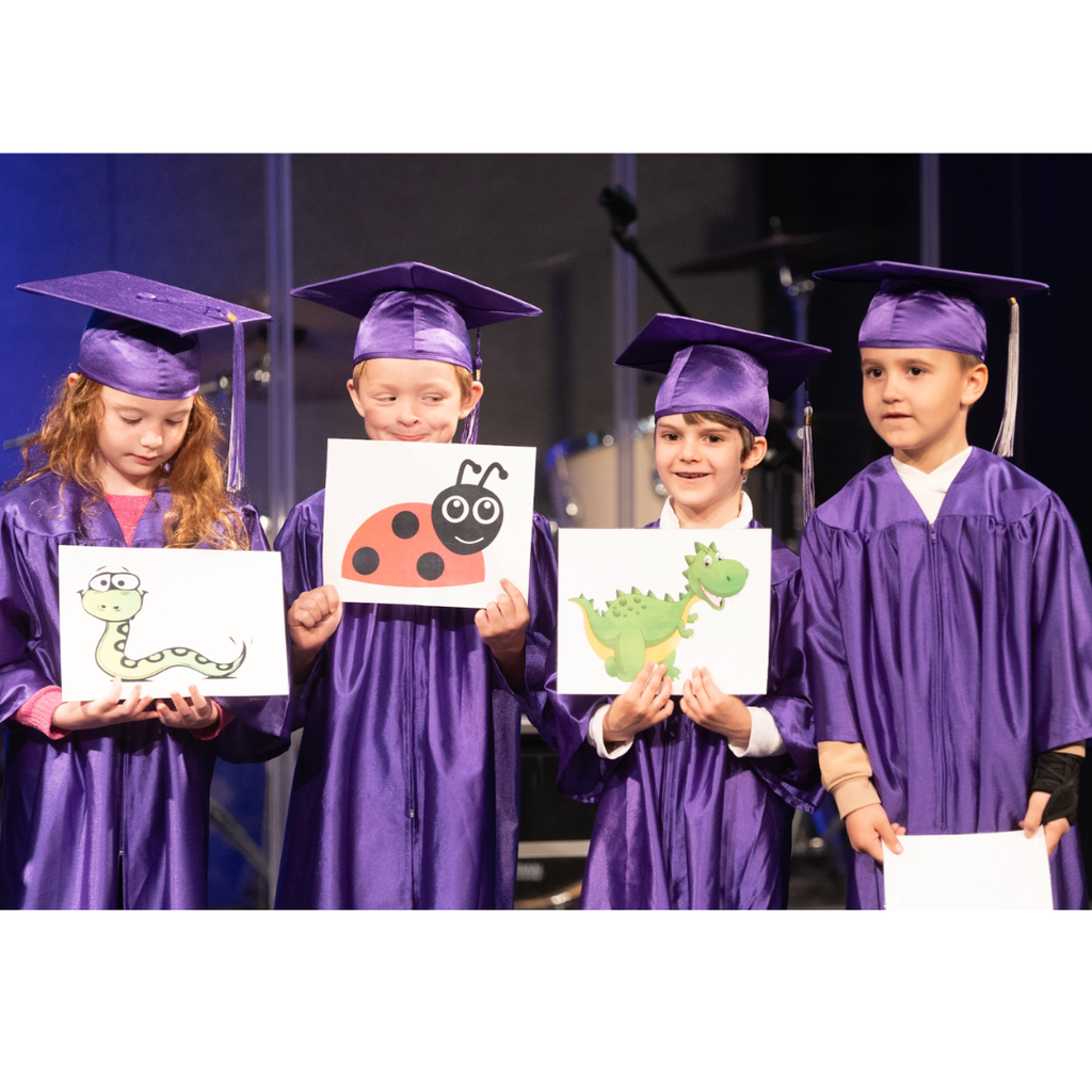 kindergarten students in caps and gowns on stage during their graduation ceremony