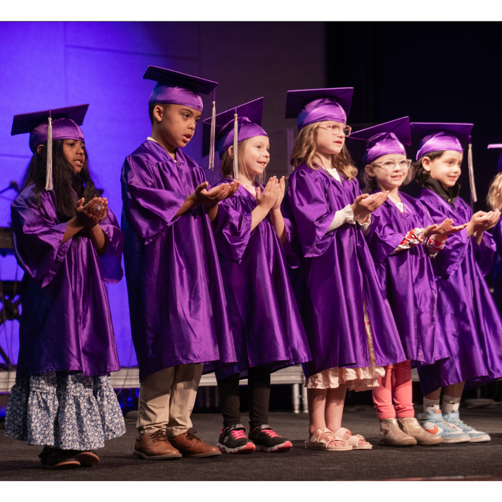 kindergarten students in caps and gowns on stage during their graduation ceremony