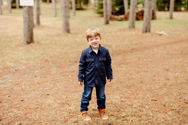 young boy standing in a forest